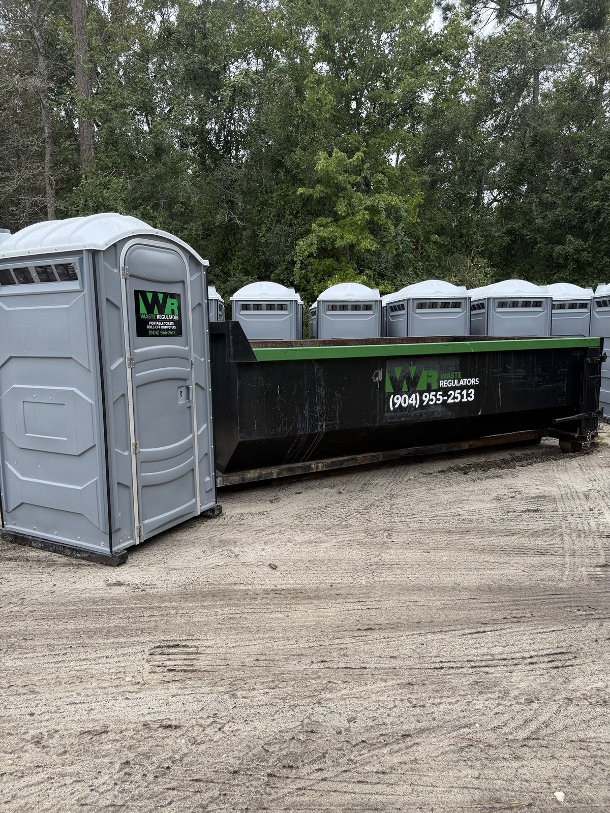 Waste Regulators portable toilets and a roll-off dumpster in the yard